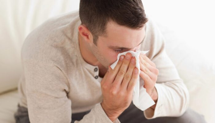 Ill man blowing his nose in his living room